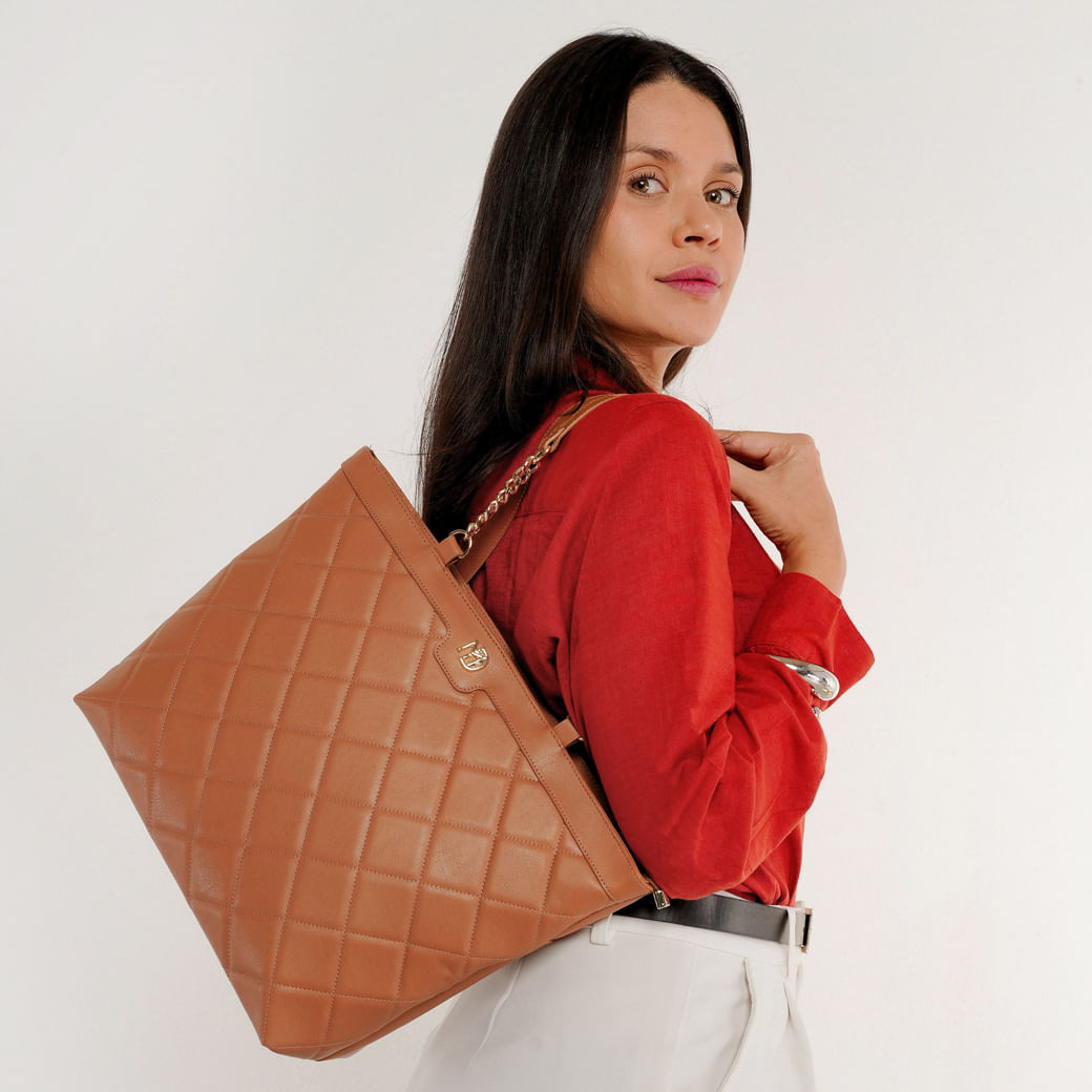 Mulher segurando bolsa Modare Totem bege em ambiente casual